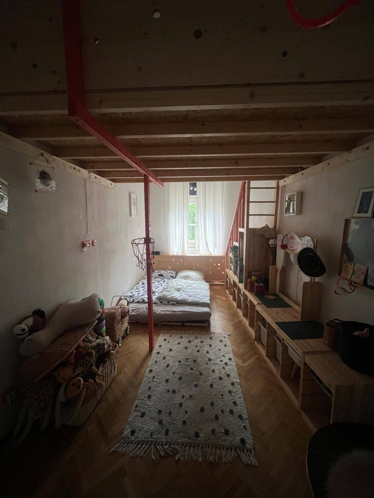 Kinderzimmer mit Hochbettkonstruktion, Holzboden und Spielzeug.