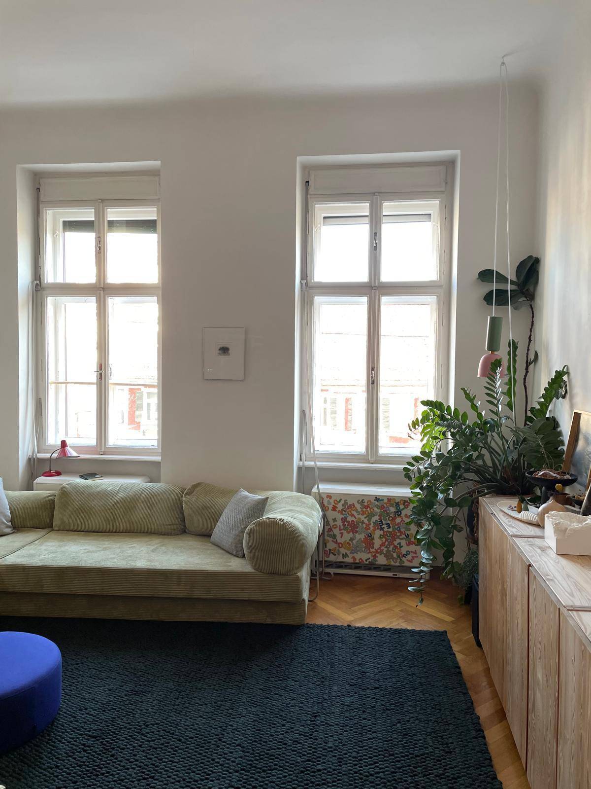Heller Wohnbereich mit großem Sofa, zwei Fenstern und einem Holzboden.