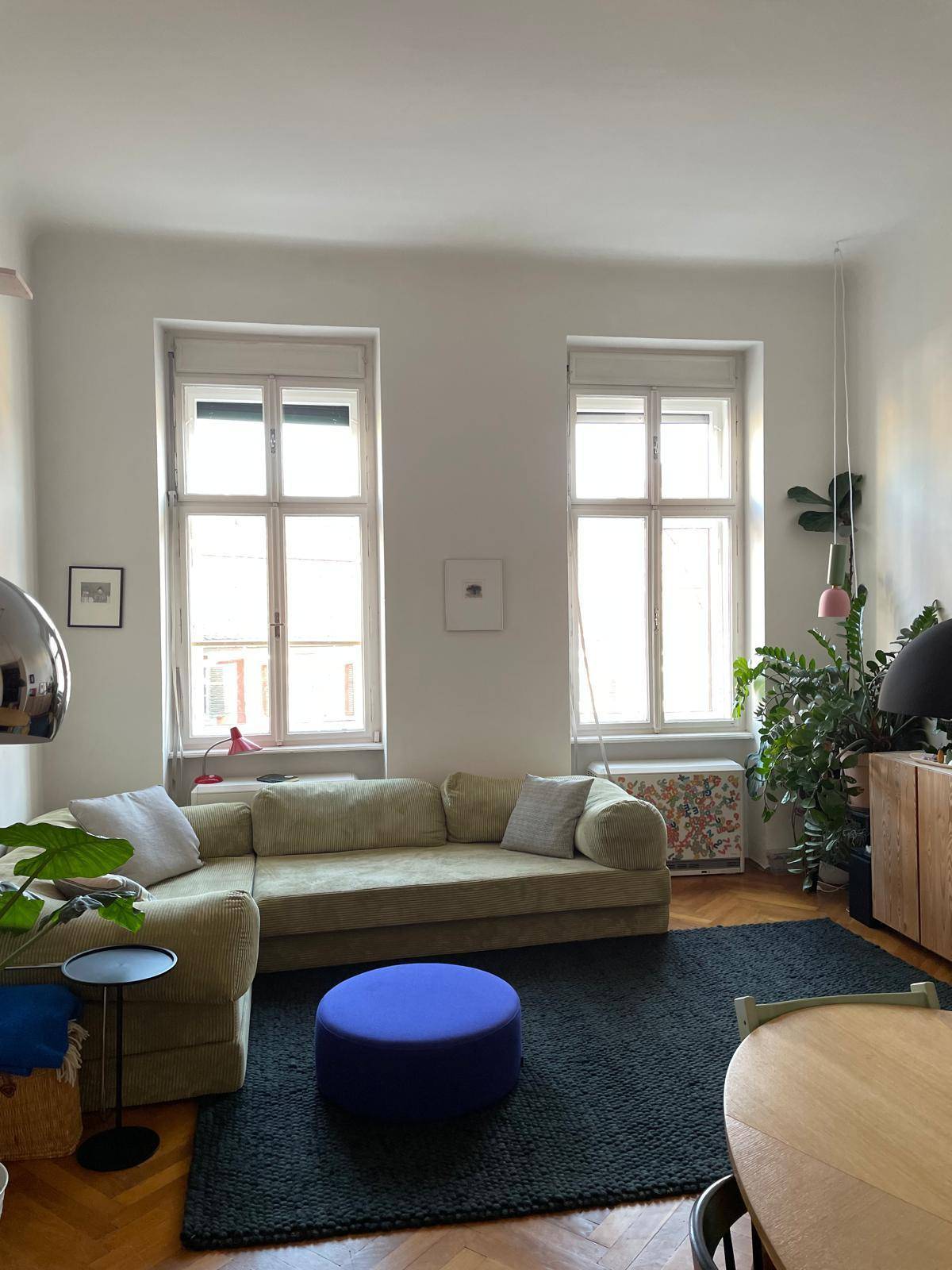 Geräumiges Wohnzimmer mit zwei großen Fenstern, bequemem Sofa und Holzboden.