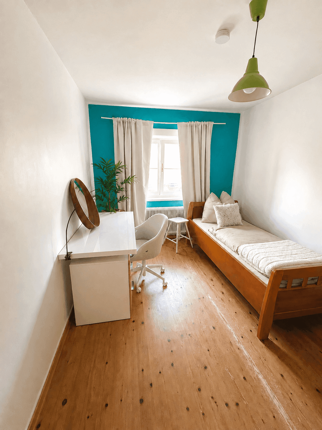 Kleines Schlafzimmer mit Einzelbett, Schreibtisch und farbiger Akzentwand in Türkis.