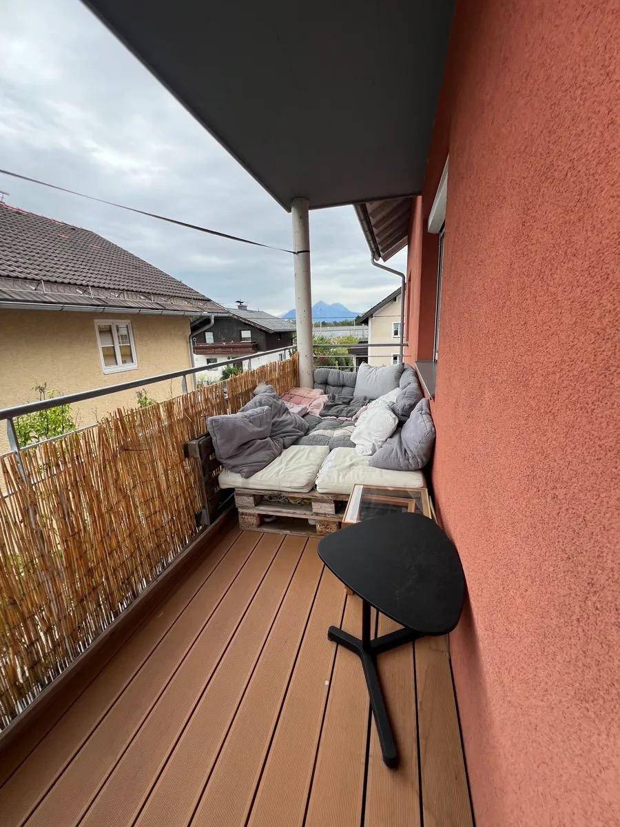 Gemütlicher Balkon mit Palettenmöbeln und einem weiten Blick auf die umliegende Landschaft und Berge.