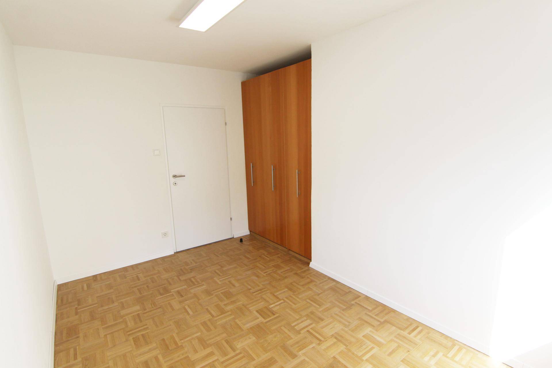Kleines Zimmer mit Parkettboden und praktischem Einbauschrank, ideal als Gäste- oder Arbeitszimmer.