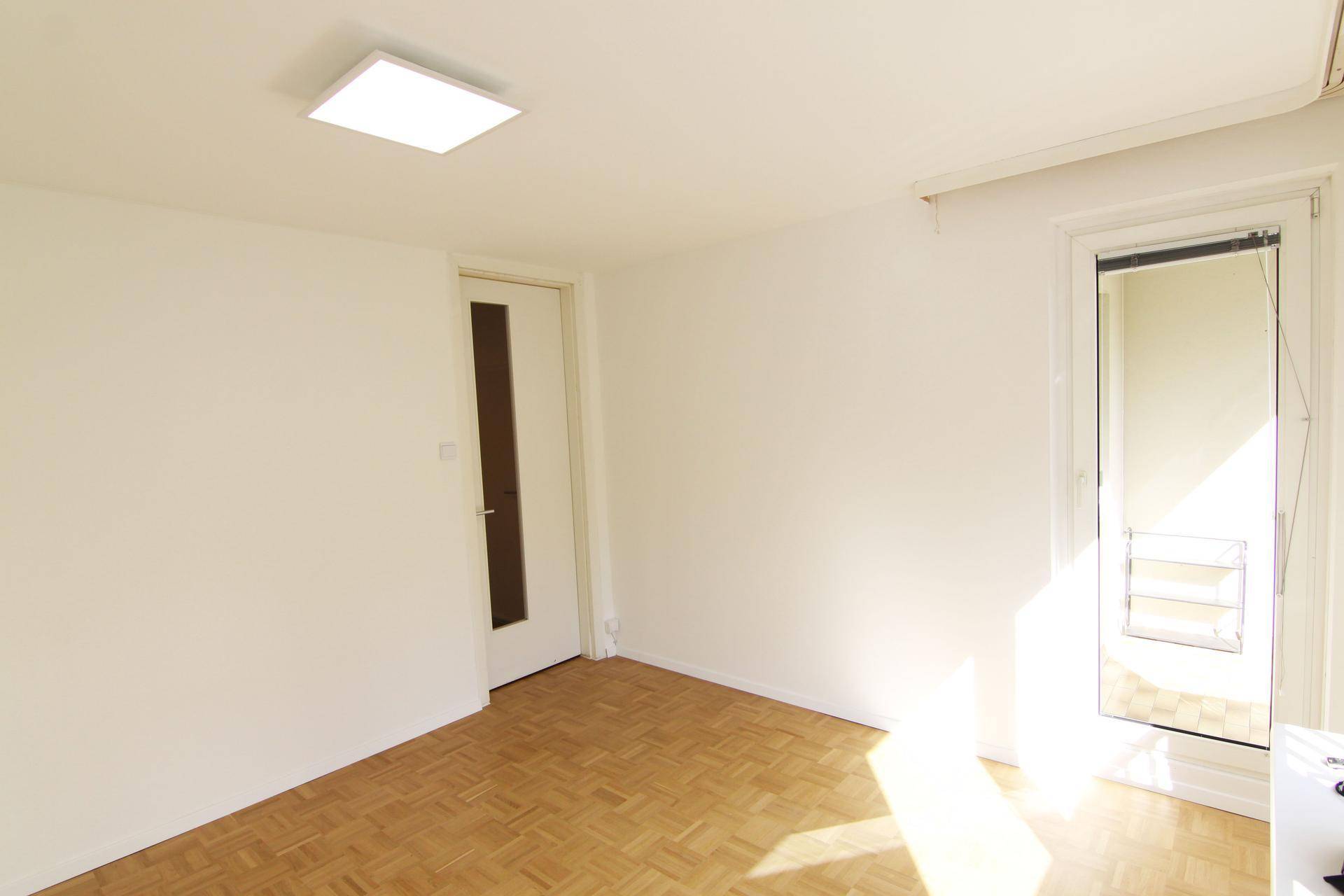 Lichtdurchflutetes Zimmer mit Parkettboden und Zugang zu einem sonnigen Balkon, einladend und hell.