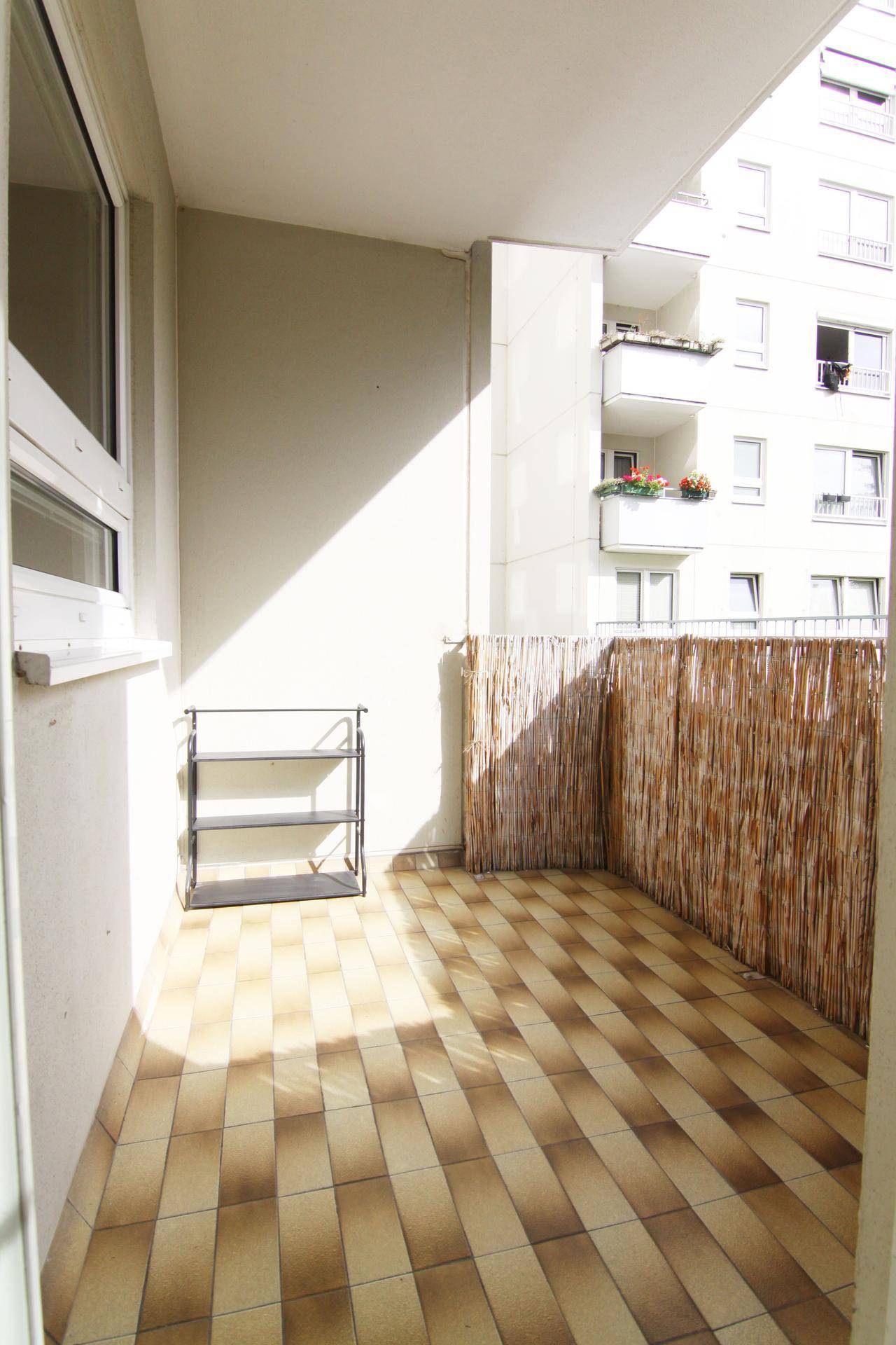 Heller Balkon mit Fliesenboden und Bambus-Sichtschutz, ideal für entspannte Stunden im Freien.