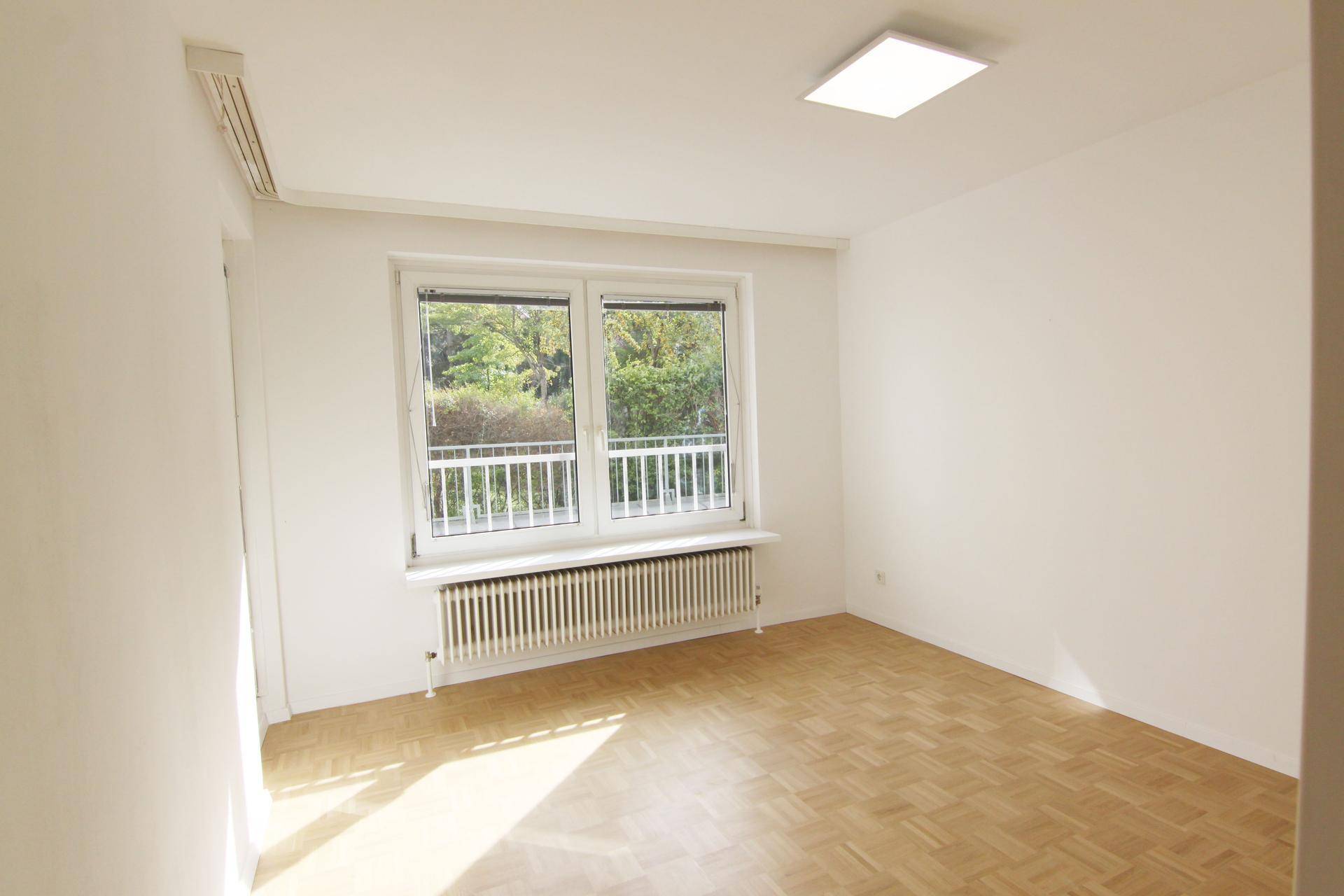 Helles Zimmer mit Parkettboden, weißen Wänden und großem Fenster, vielseitig nutzbar.
