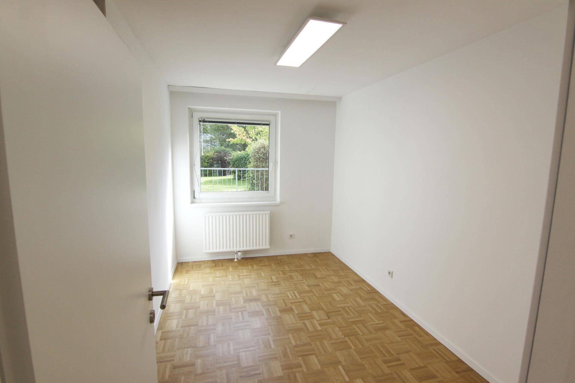 Kleines helles Zimmer mit Parkettboden, weißen Wänden und Fenster, ideal als Kinder- oder Arbeitszimmer.