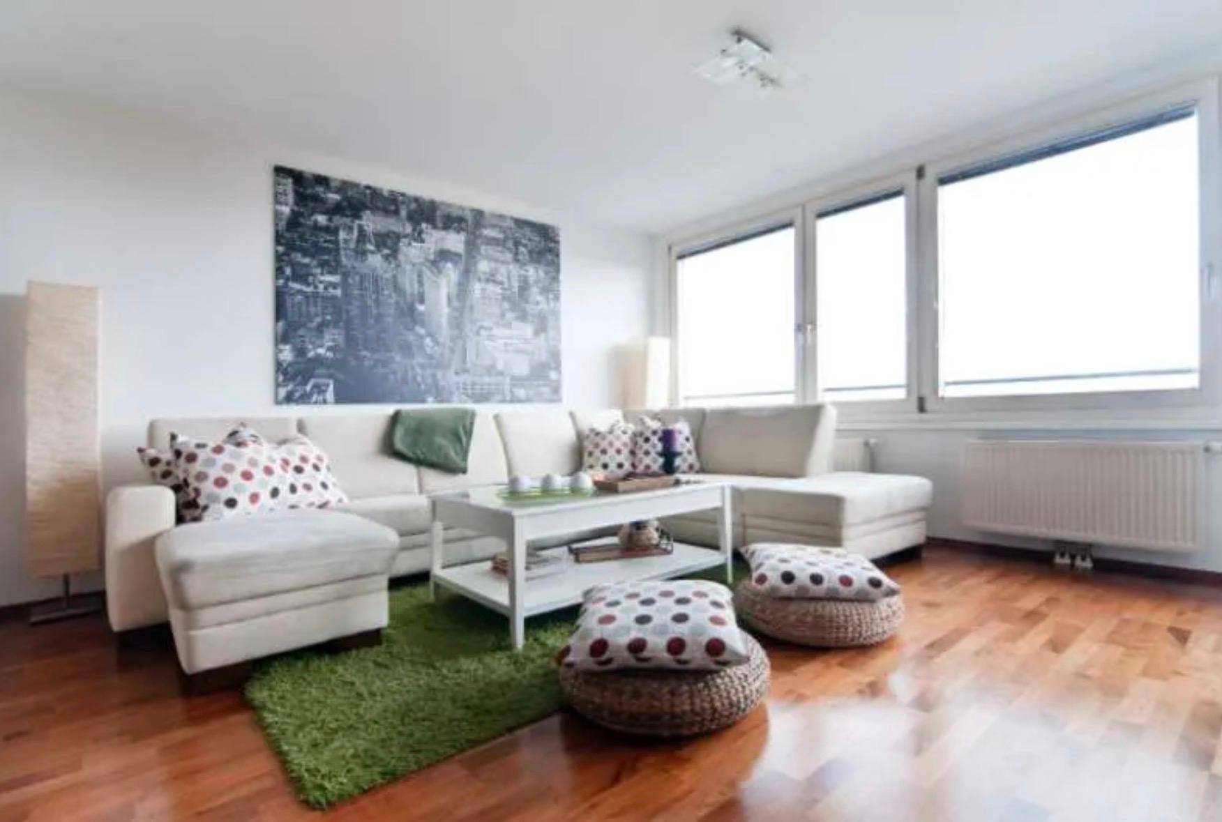 Gemütliches Wohnzimmer mit Holzboden, bequemer Couch und großem Wandbild.
