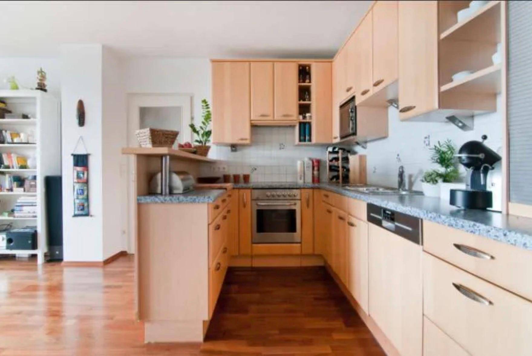 Helle Einbauküche mit Holzfronten, Granitarbeitsplatte und integrierten Geräten.