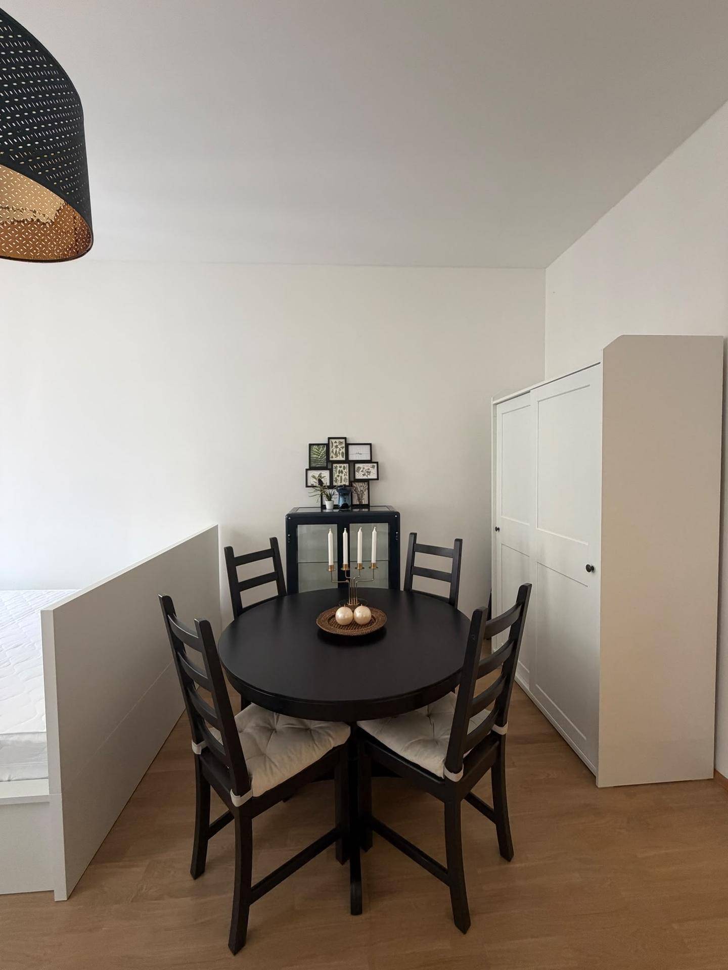 Essbereich mit rundem Tisch und Stühlen, neben einem praktischen Kleiderschrank im Studio-Apartment.