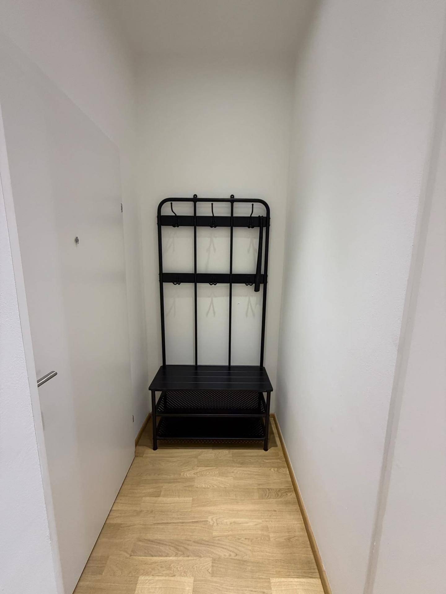 Praktischer Eingangsbereich mit Garderobe und Schuhablage, ideal für kleine Apartments.