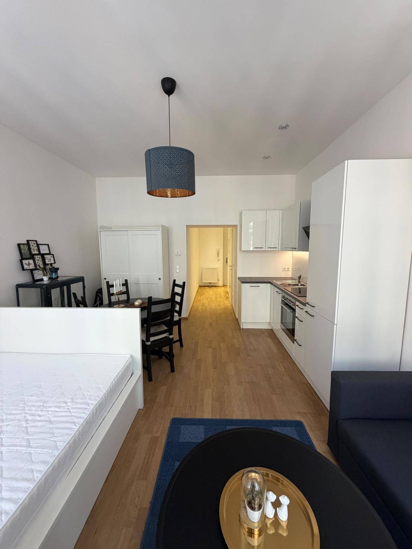 Weitläufiger Blick durch das Studio-Apartment mit Schlafbereich, Essplatz und funktionaler Küchenzeile.