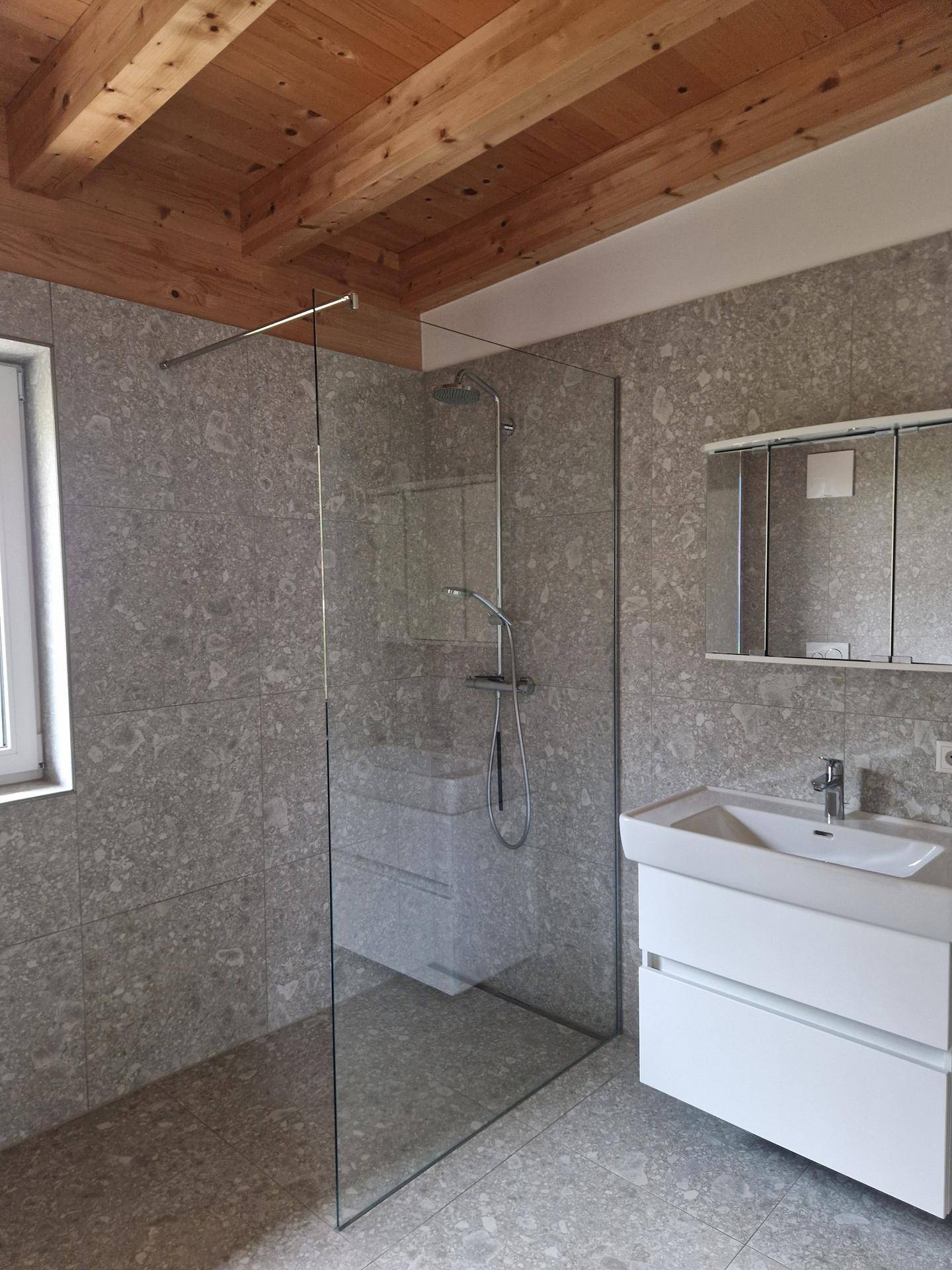Helles Badezimmer mit begehbarer Dusche, modernem Waschtisch und Fenster für natürliches Licht.