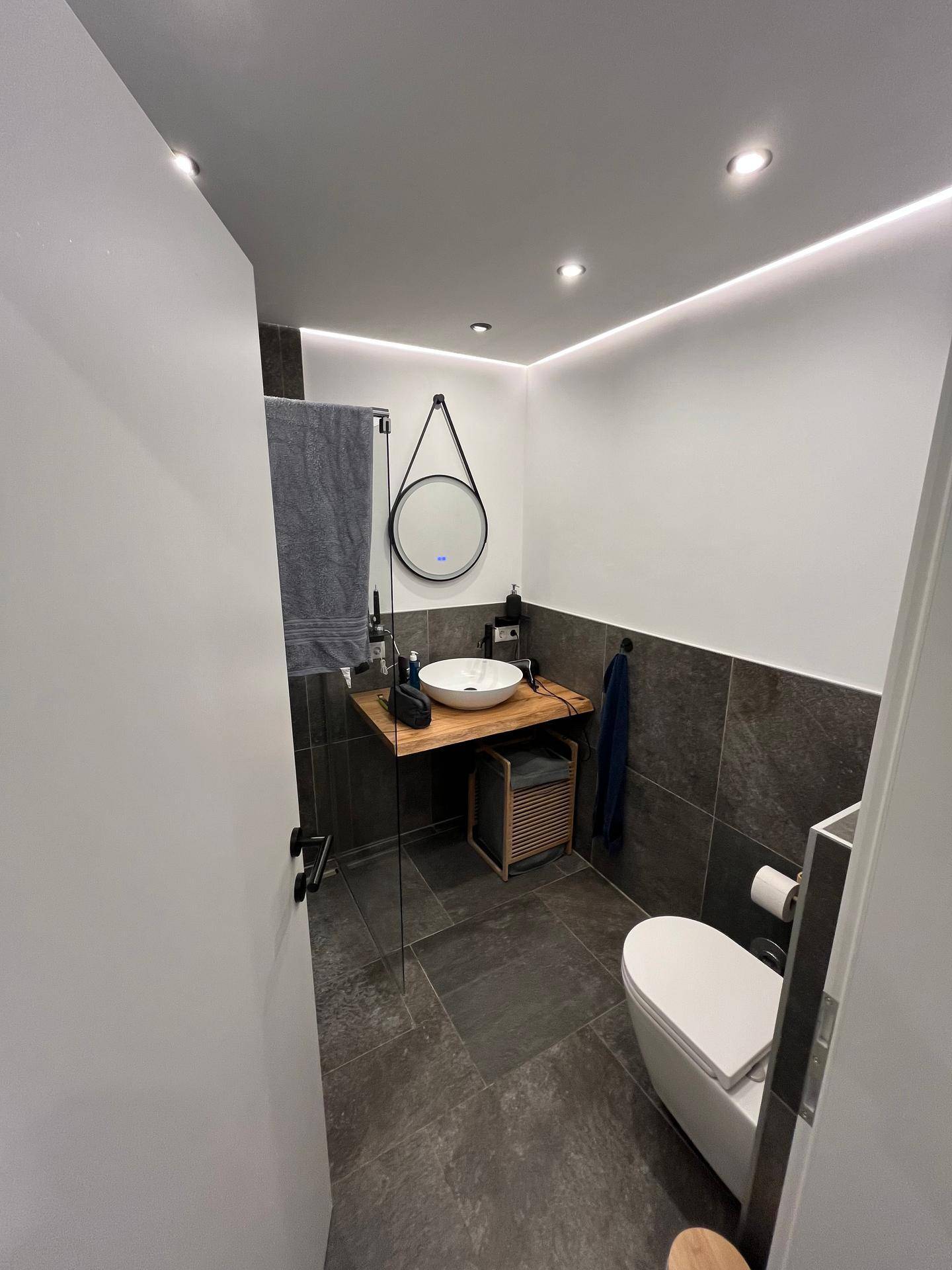 Modernes Badezimmer mit Aufsatzwaschbecken, WC und stilvoller Beleuchtung.