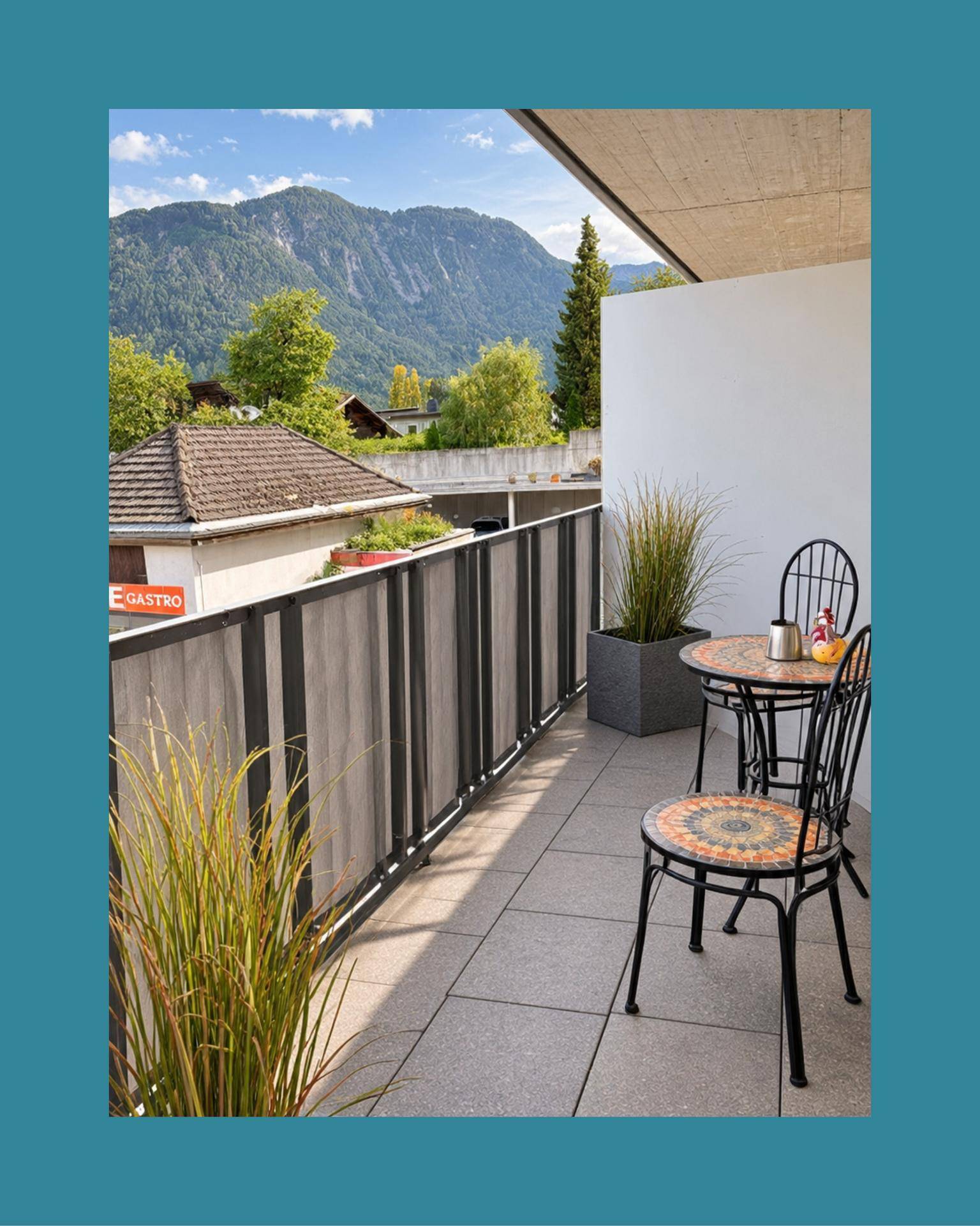 Sonniger Balkon mit Sitzgelegenheiten, Pflanzen und einem malerischen Blick auf die Berge.