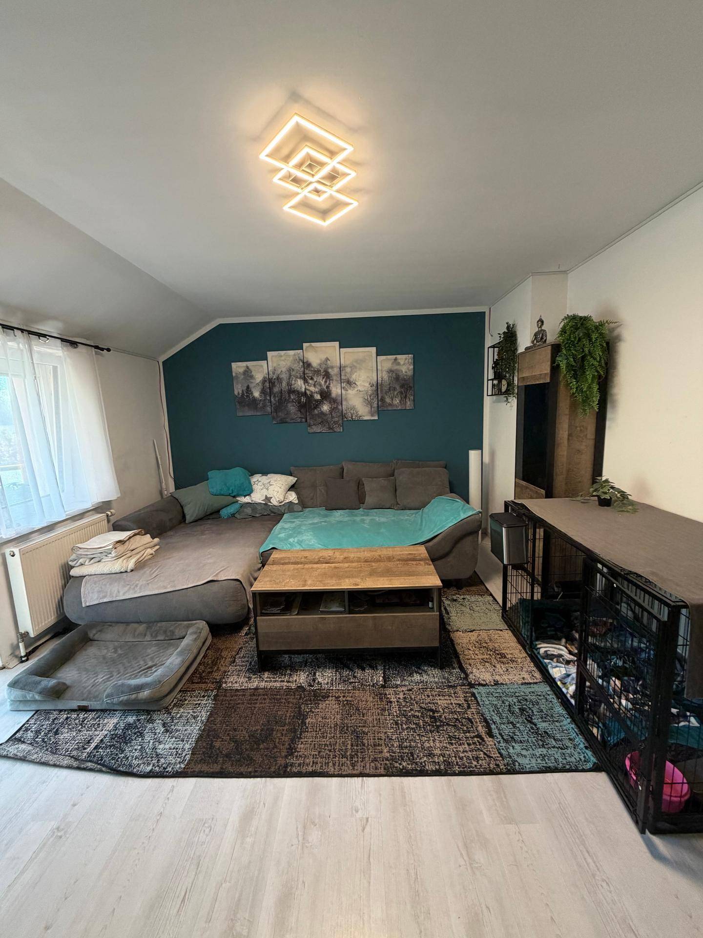 Helles Wohnzimmer mit bequemer Sitzecke, modernem Couchtisch und dekorativer Wandgestaltung in Türkis.