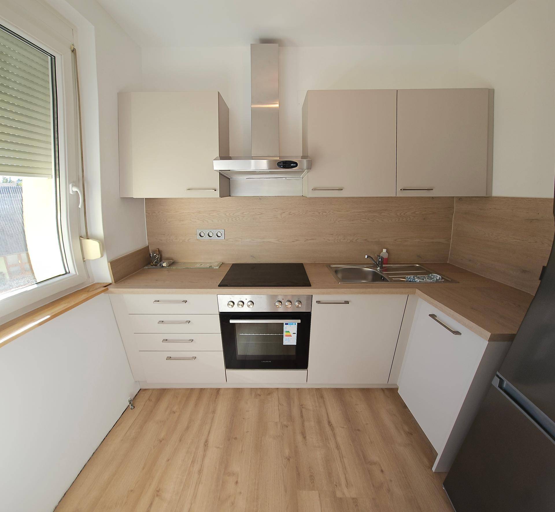 Moderne Einbauküche in Beige mit Holzoptik-Arbeitsplatte, ausgestattet mit Herd und Dunstabzugshaube.