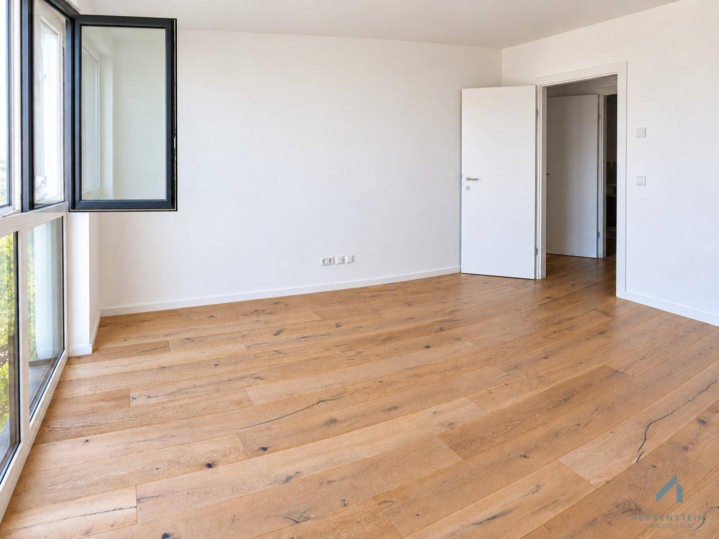 Heller Raum mit Holzparkett und großen Fenstern, die eine angenehme Wohnatmosphäre schaffen.