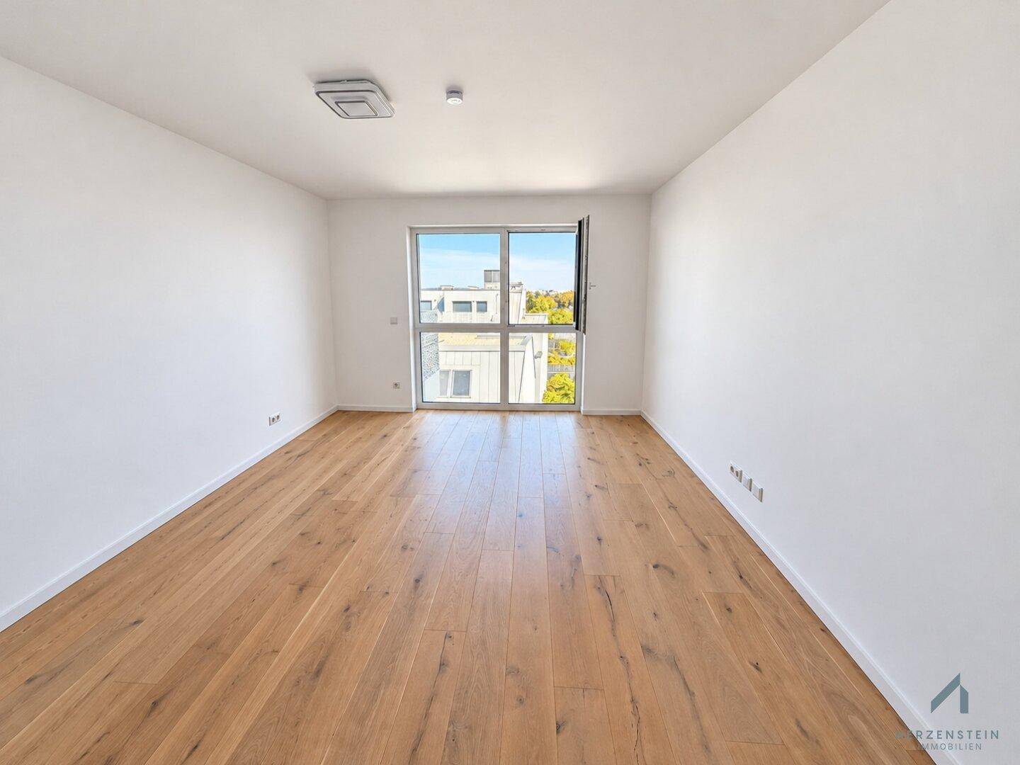 Freundliches Zimmer mit Holzparkett und einem großen Fenster, das den Raum gut belichtet.