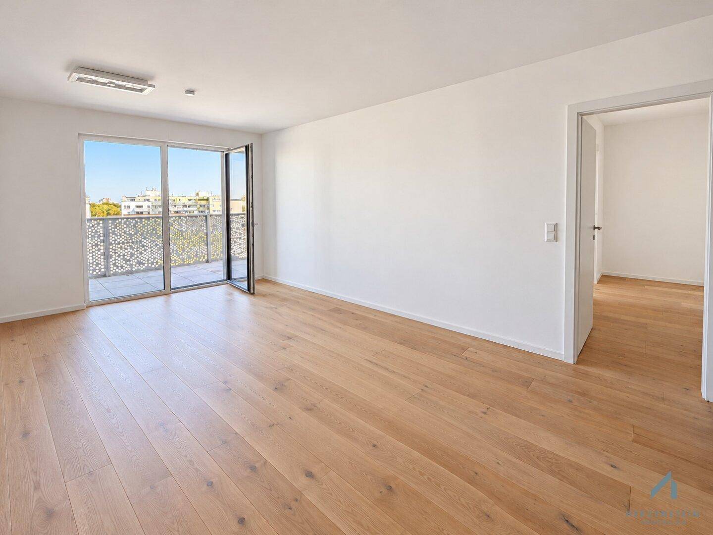 Helles Wohnzimmer mit Echtholzparkett und Zugang zu einem großen Balkon.