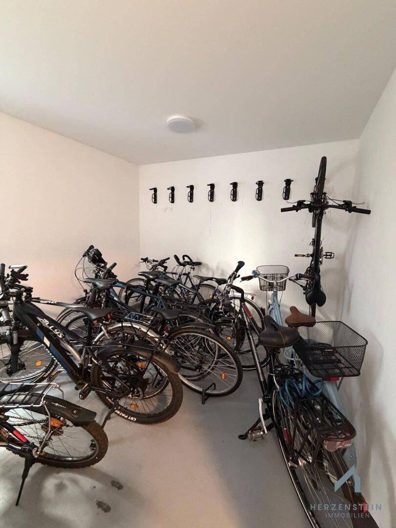 Gemeinschaftlicher Fahrradraum mit zahlreichen Fahrrädern und Wandhaken zur Aufbewahrung.
