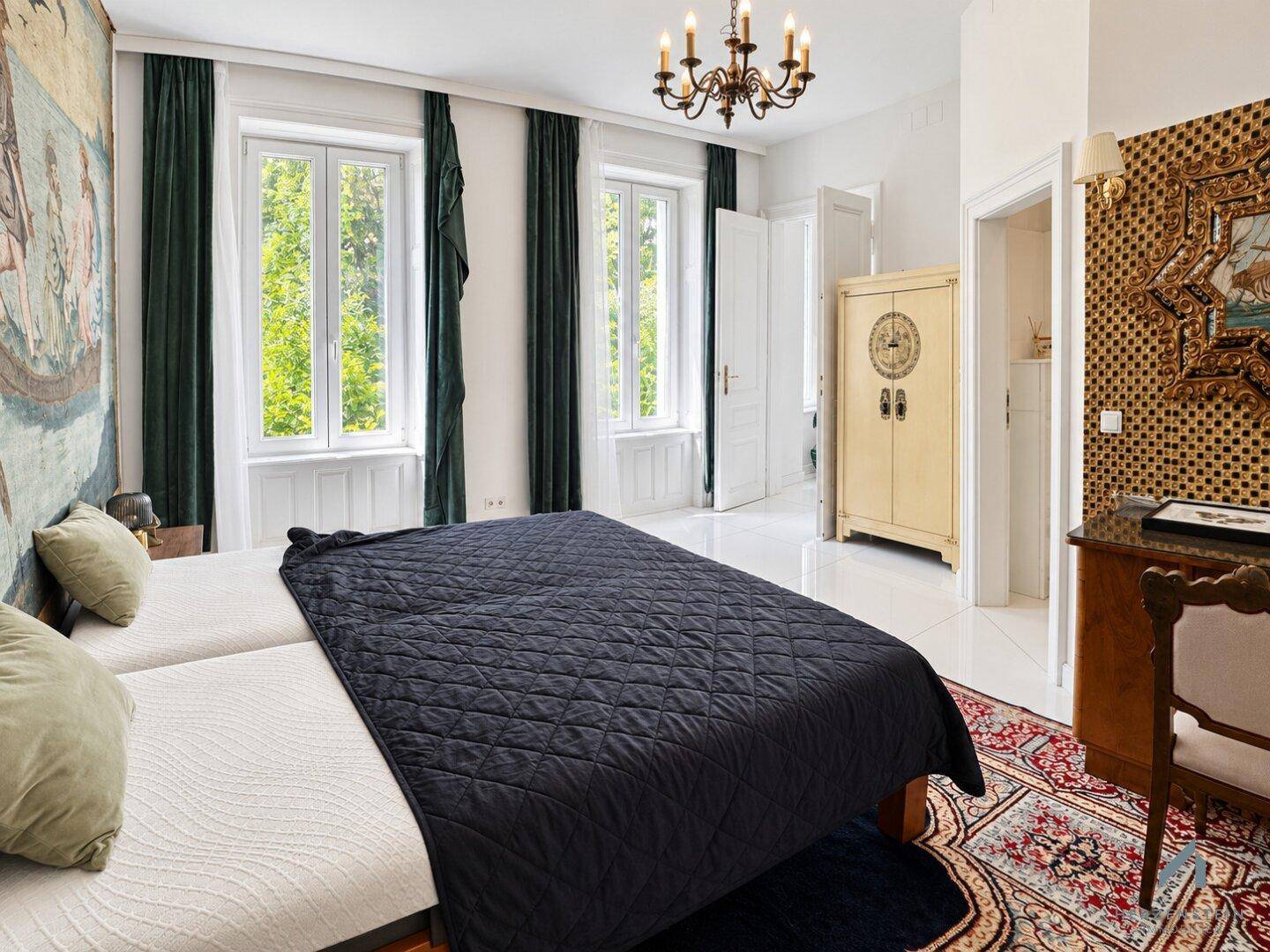 Helles Schlafzimmer mit zwei Einzelbetten, eleganten Vorhängen und Blick ins Grüne.