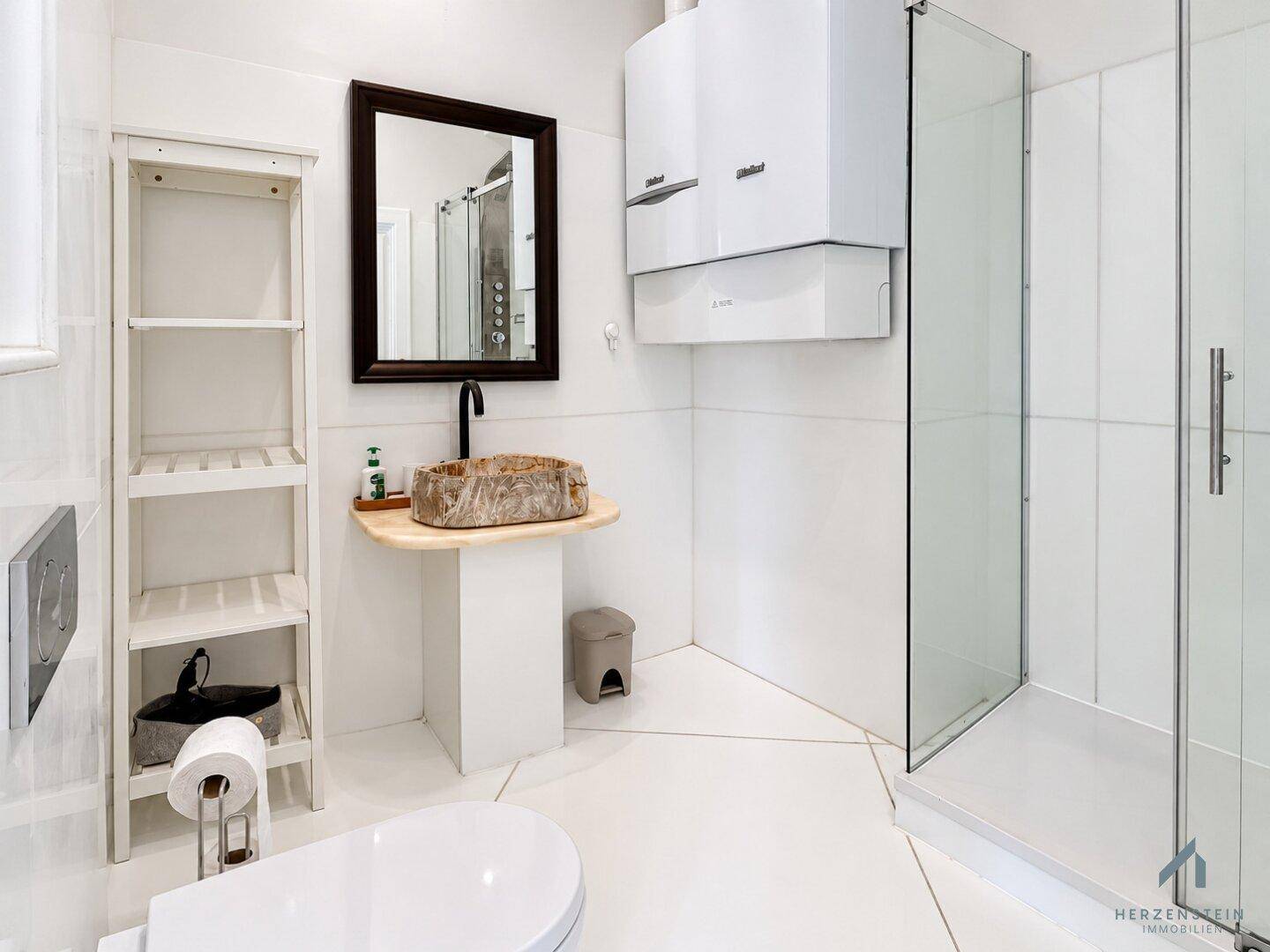 Helles Badezimmer mit Duschkabine, modernem Waschbecken und weißer Wandverkleidung.