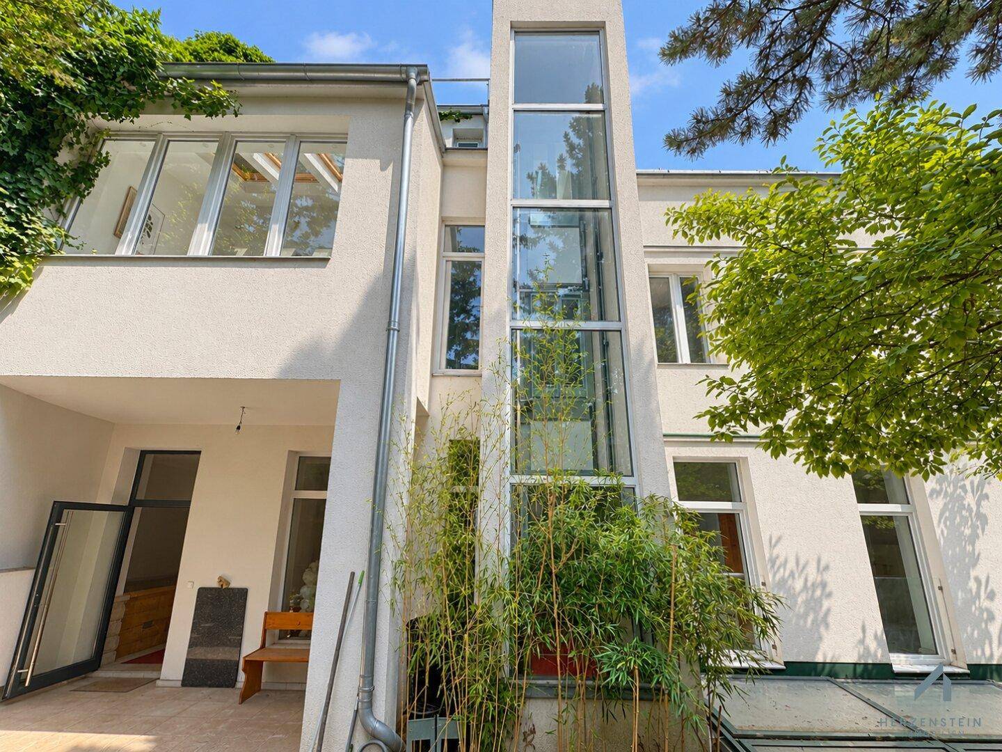 Moderne Hausfassade mit großen Fenstern und einem externen Glasaufzug.