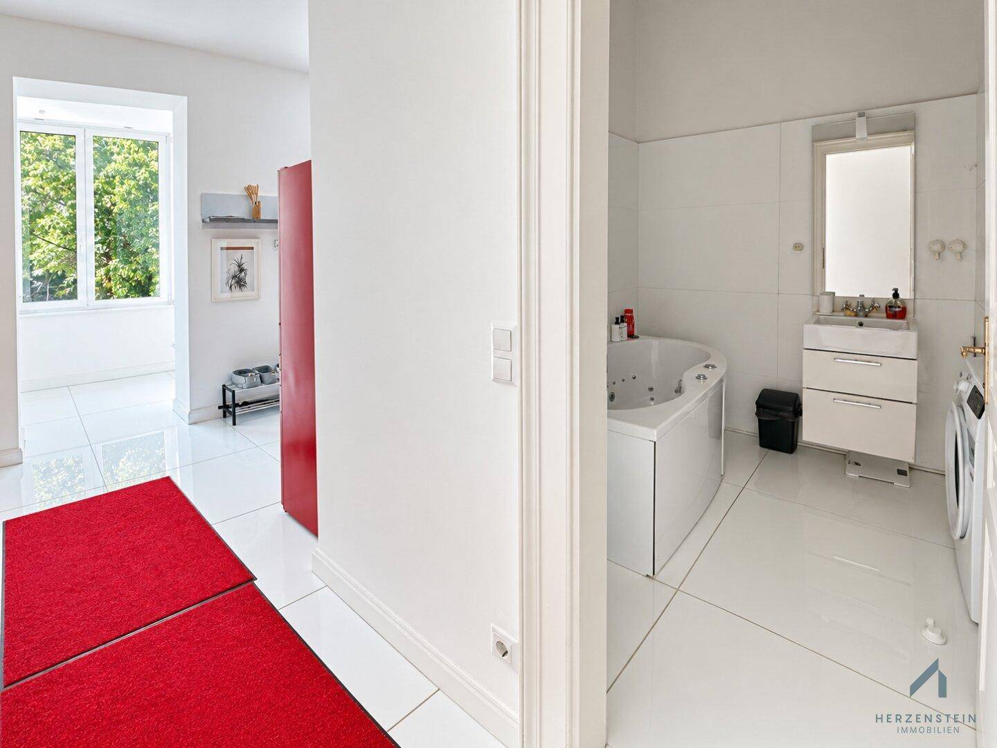 Heller Flur mit Blick in ein modernes Badezimmer mit Whirlpool-Badewanne.