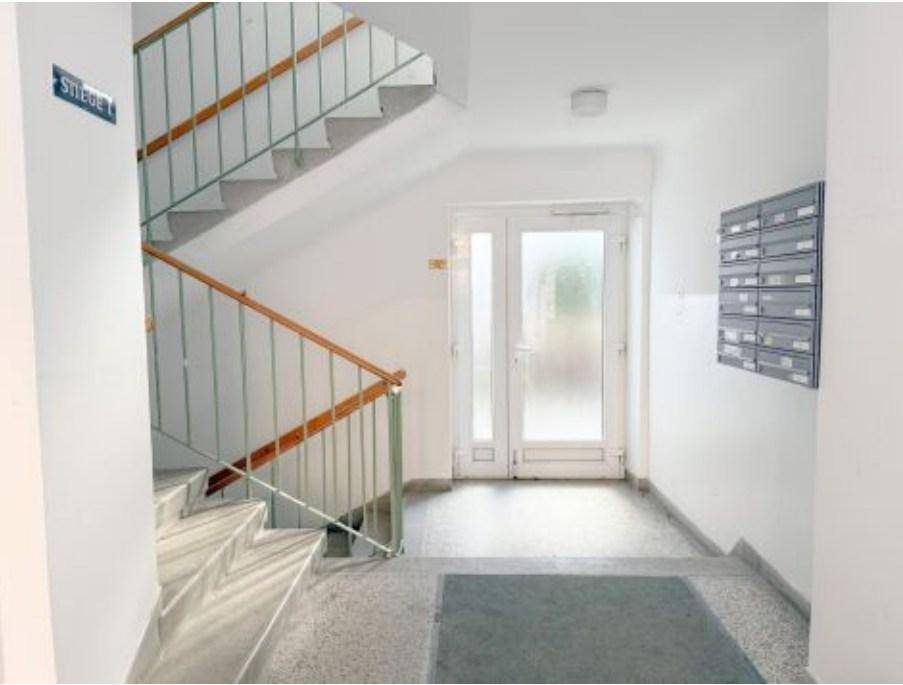 Heller Treppenaufgang in einem Mehrfamilienhaus mit Briefkästen und Zugangstür.