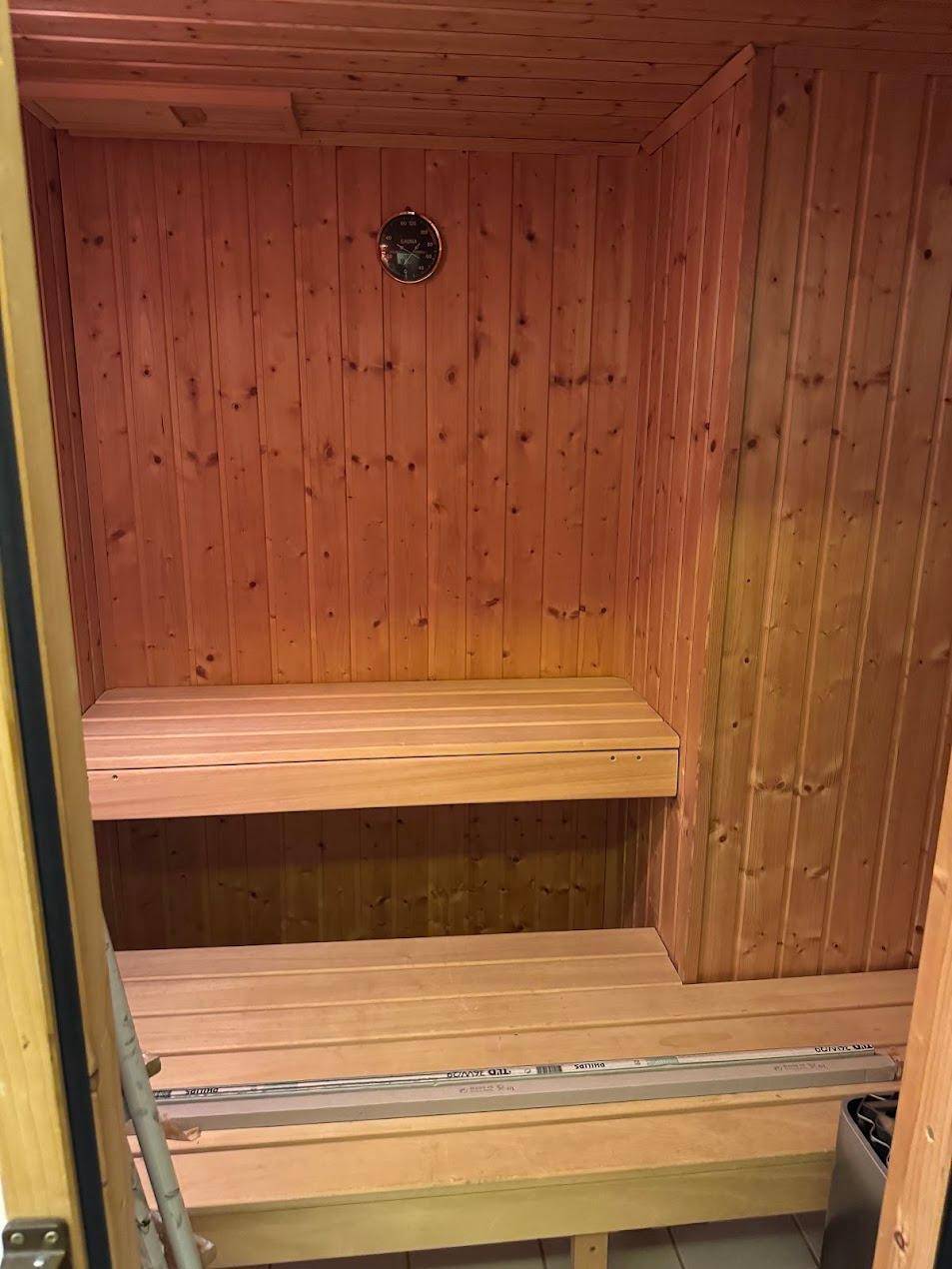 Holzverkleidete Sauna mit Bänken und Heizofen, bereit zur Nutzung und Entspannung.