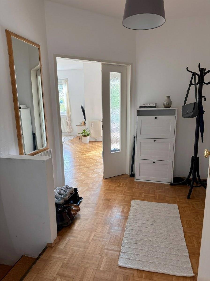 Heller Eingangsbereich mit Parkettboden, großem Spiegel und praktischer Garderobe.