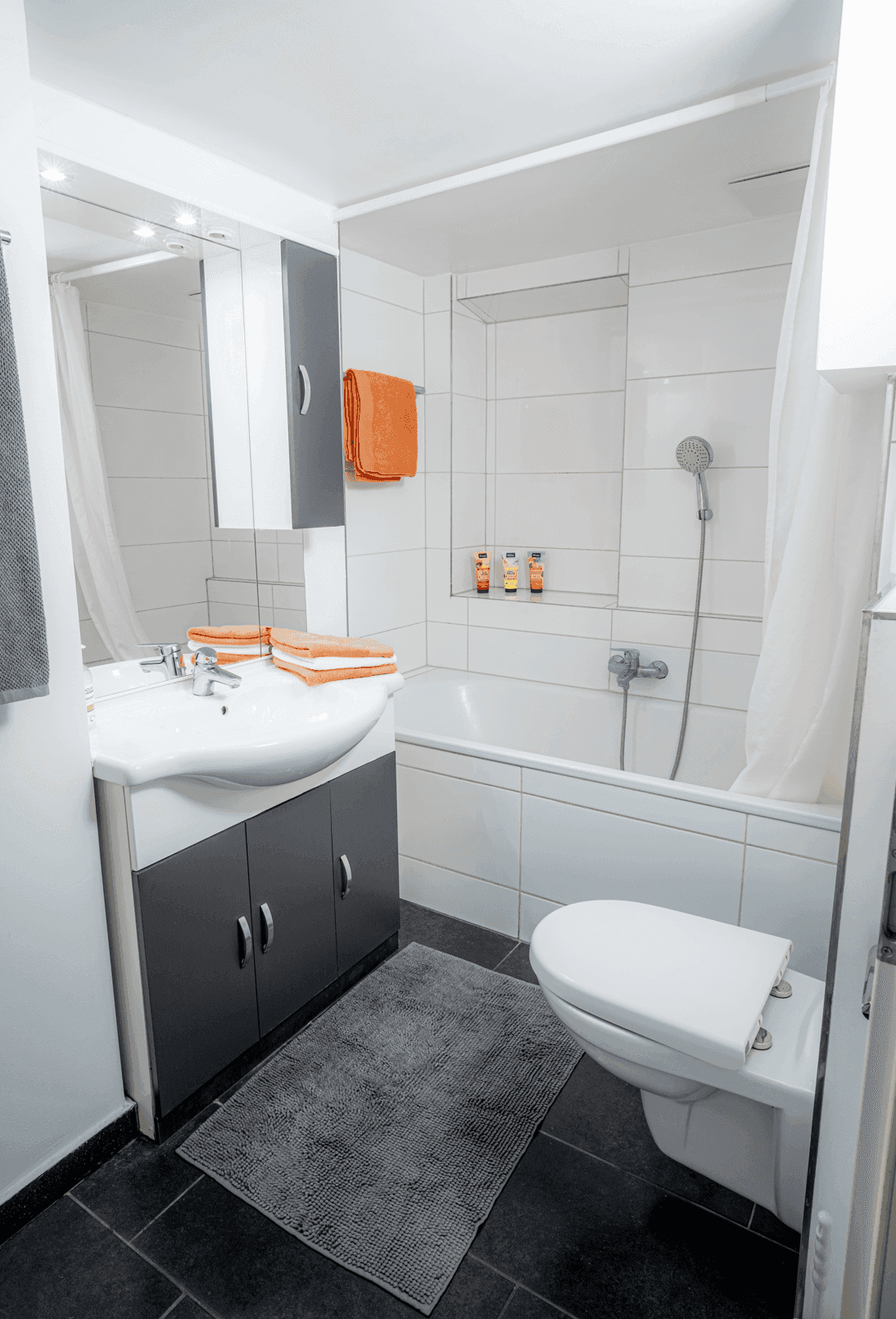 Modernes Badezimmer mit Badewanne, Dusche, Waschbecken und Toilette, hell gefliest.