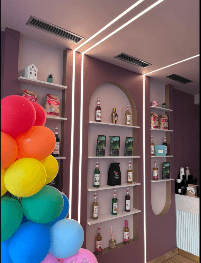 Dekorative Wandregale mit Produkten und bunten Ballons in einem stilvollen Café-Interieur.