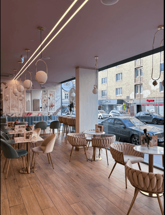 Gemütlicher Sitzbereich eines Cafés mit modernen Möbeln, Holzboden und Blick auf die Straße.