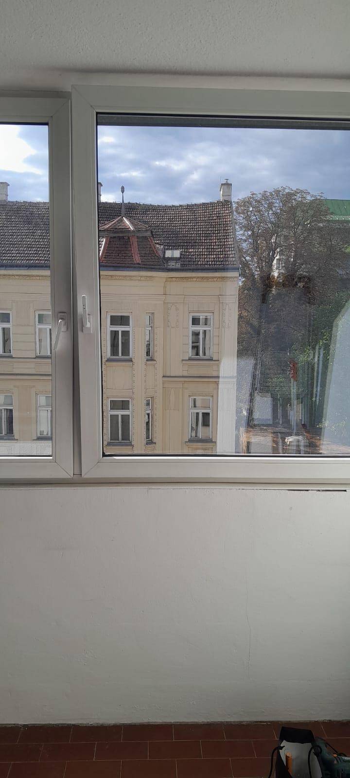 Fensterblick auf ein historisches Gebäude mit traditionellem Dach und vielen Fenstern.