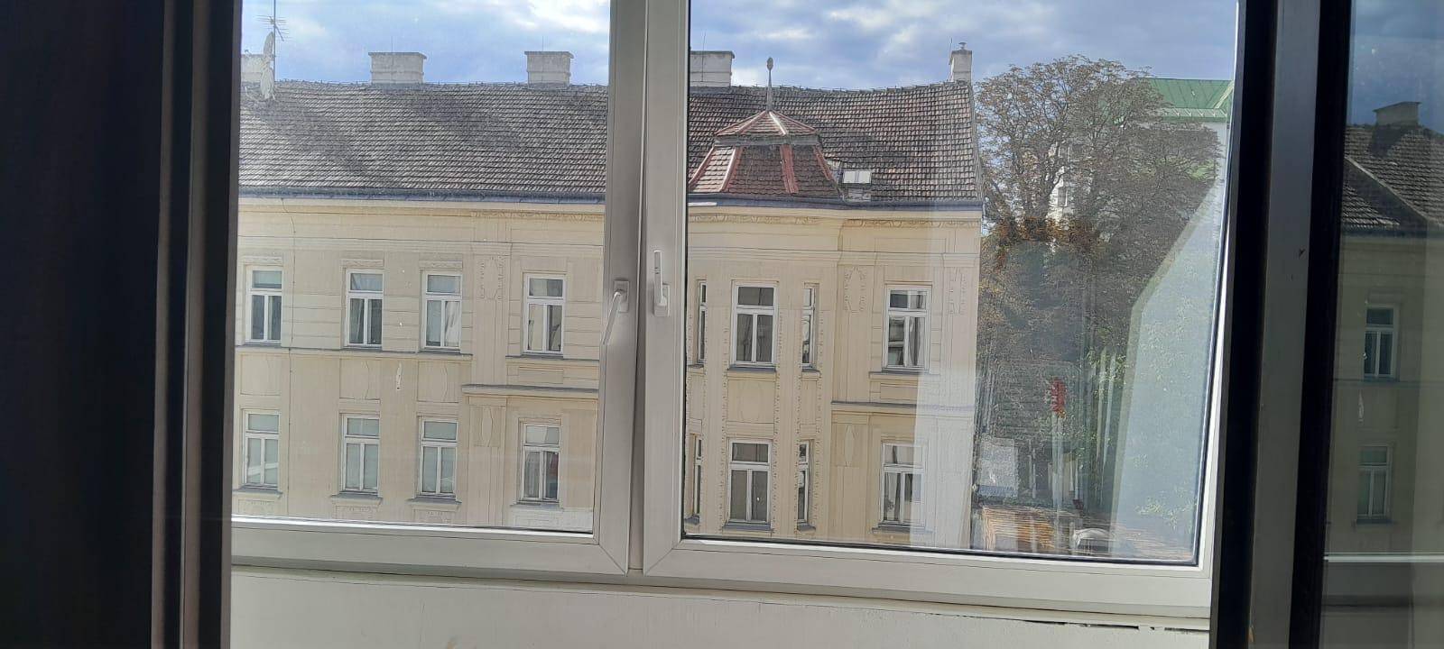 Blick aus dem Fenster auf ein gegenüberliegendes, älteres Gebäude mit klassischer Architektur.