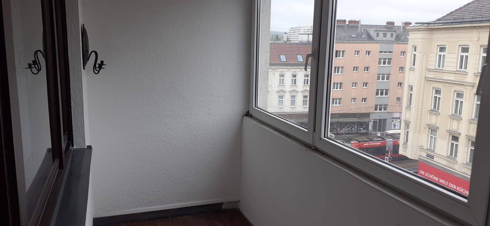 Kleiner verglaster Balkon mit Blick auf die Stadt und umliegende Gebäude.