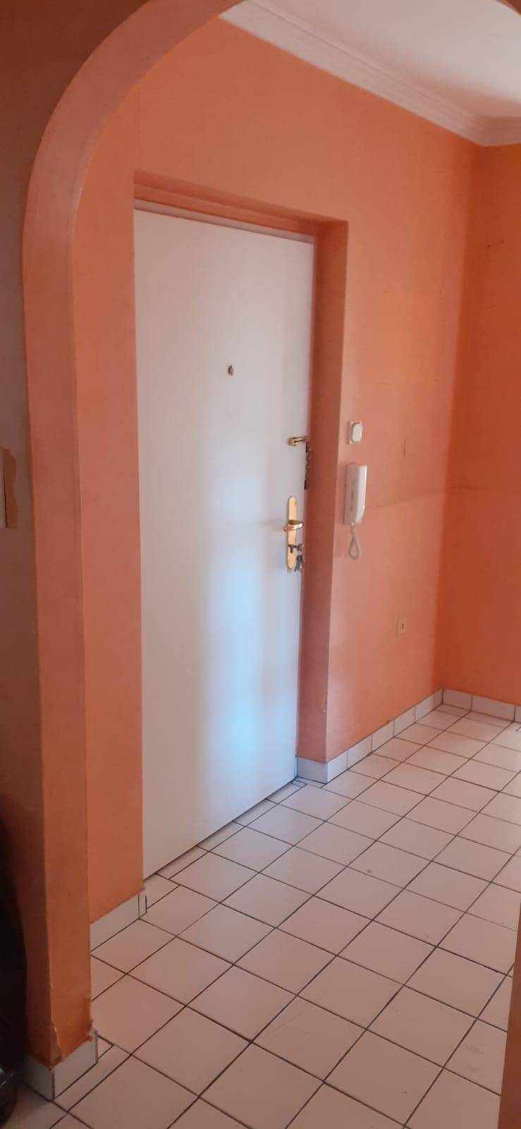 Eingangstür im Flur mit orangefarbenen Wänden und Fliesenboden.