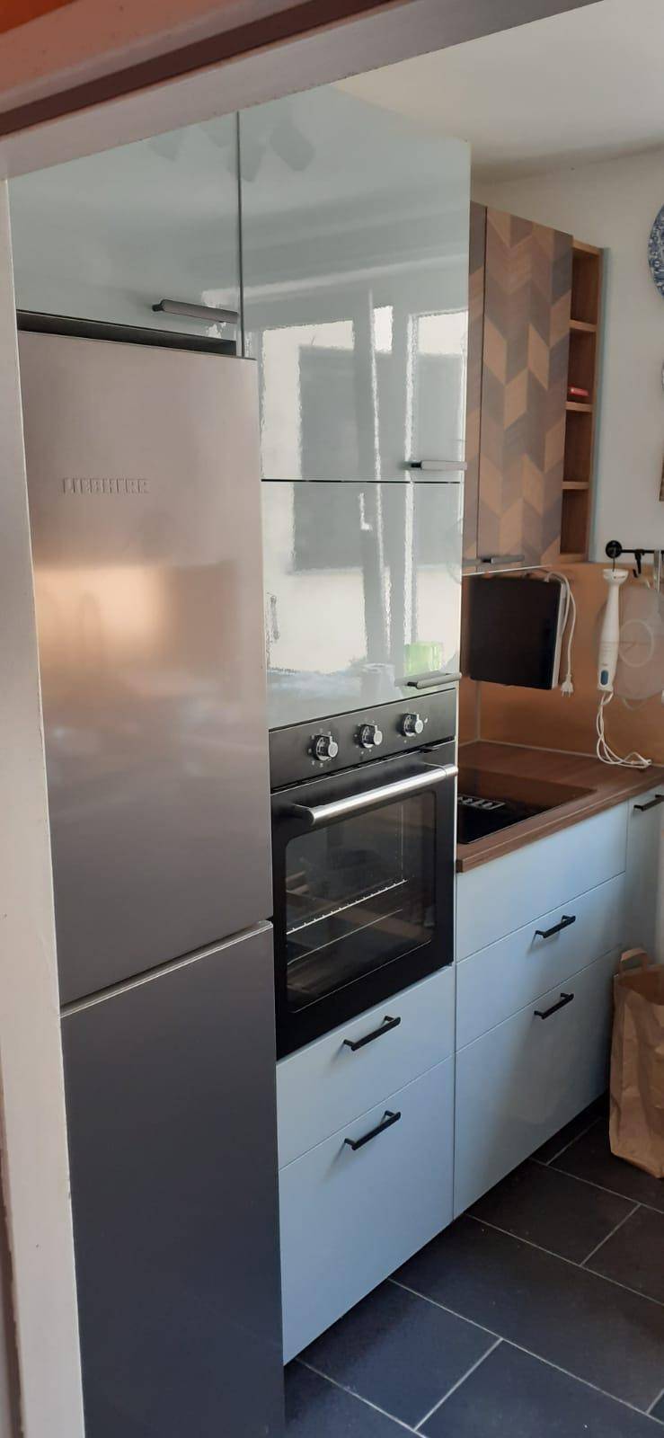 Einbauküche mit integriertem Kühlschrank, Backofen und modernen hellen Schränken.