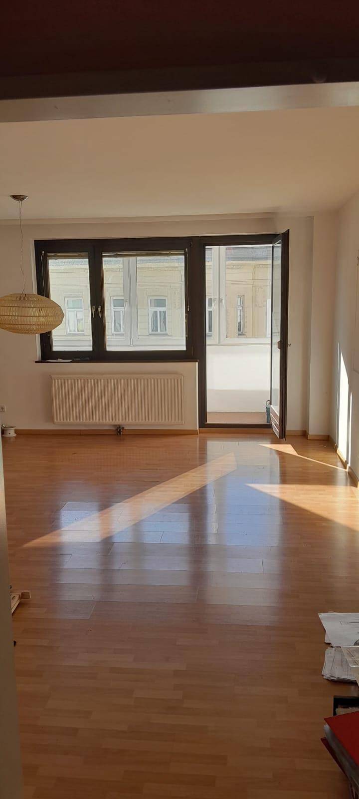 Lichtdurchflutetes Wohnzimmer mit Holzboden und Blick nach draußen, ideal für sonnige Tage.