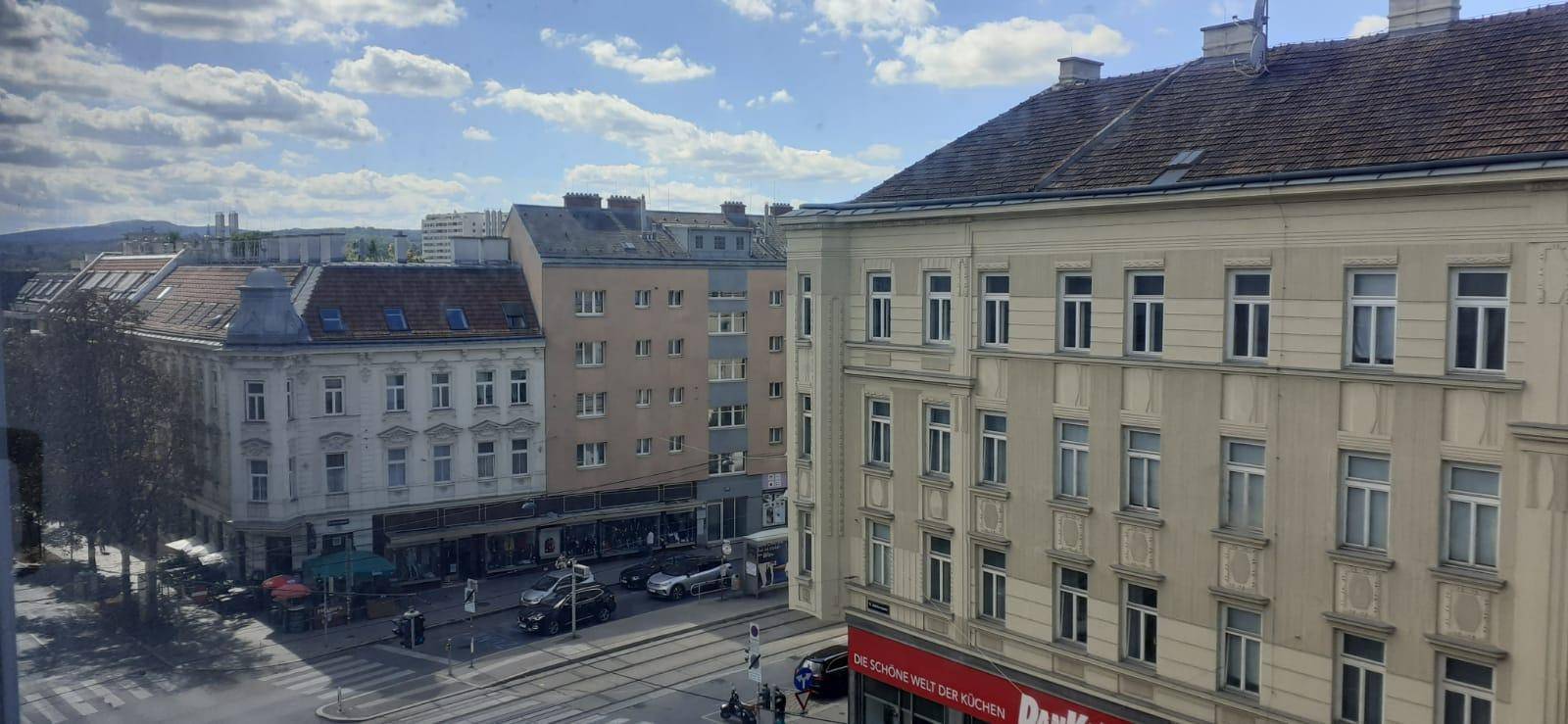 Weitläufiger Blick über eine belebte Stadtstraße mit verschiedenen Gebäuden und Verkehr.