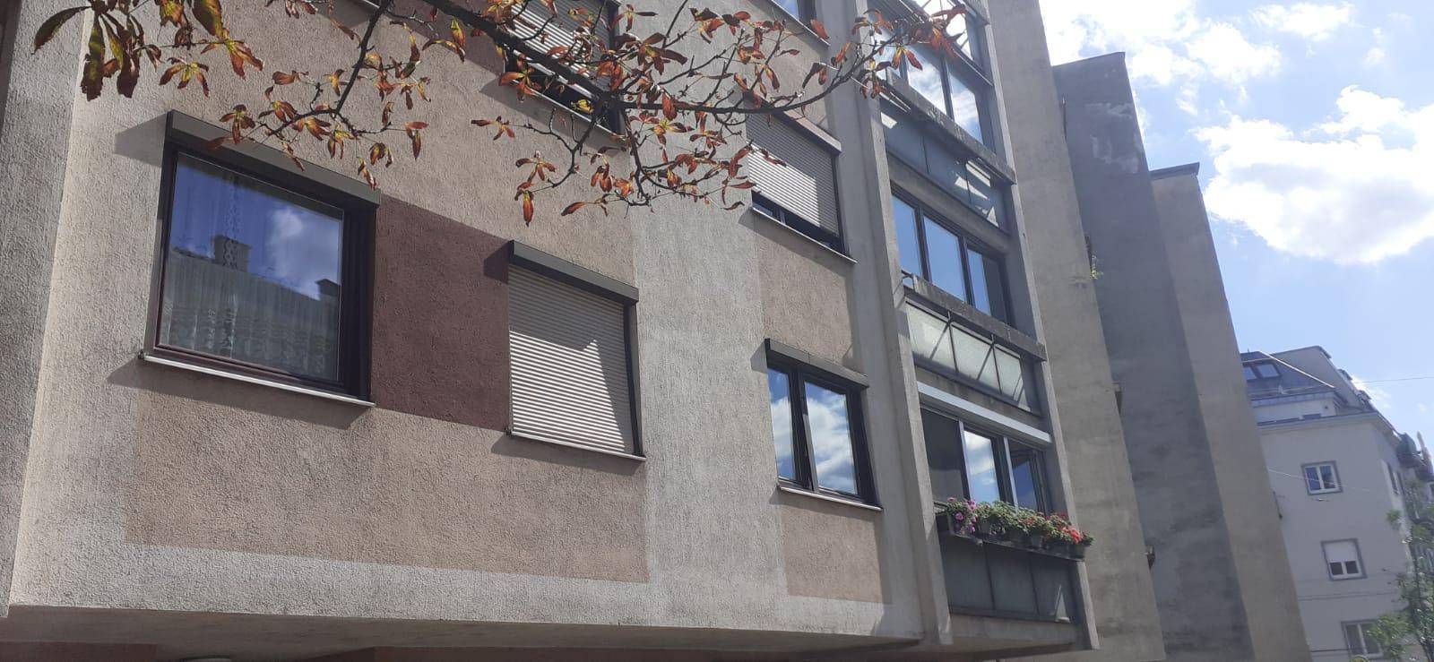 Fassade eines Wohngebäudes mit Fenstern, Rollläden und einem Blumenkasten.