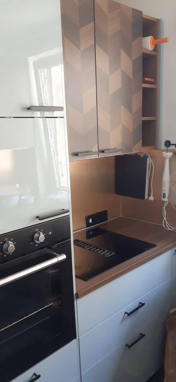 Küchenbereich mit integriertem Backofen, Kochfeld und stilvollen Oberschränken.