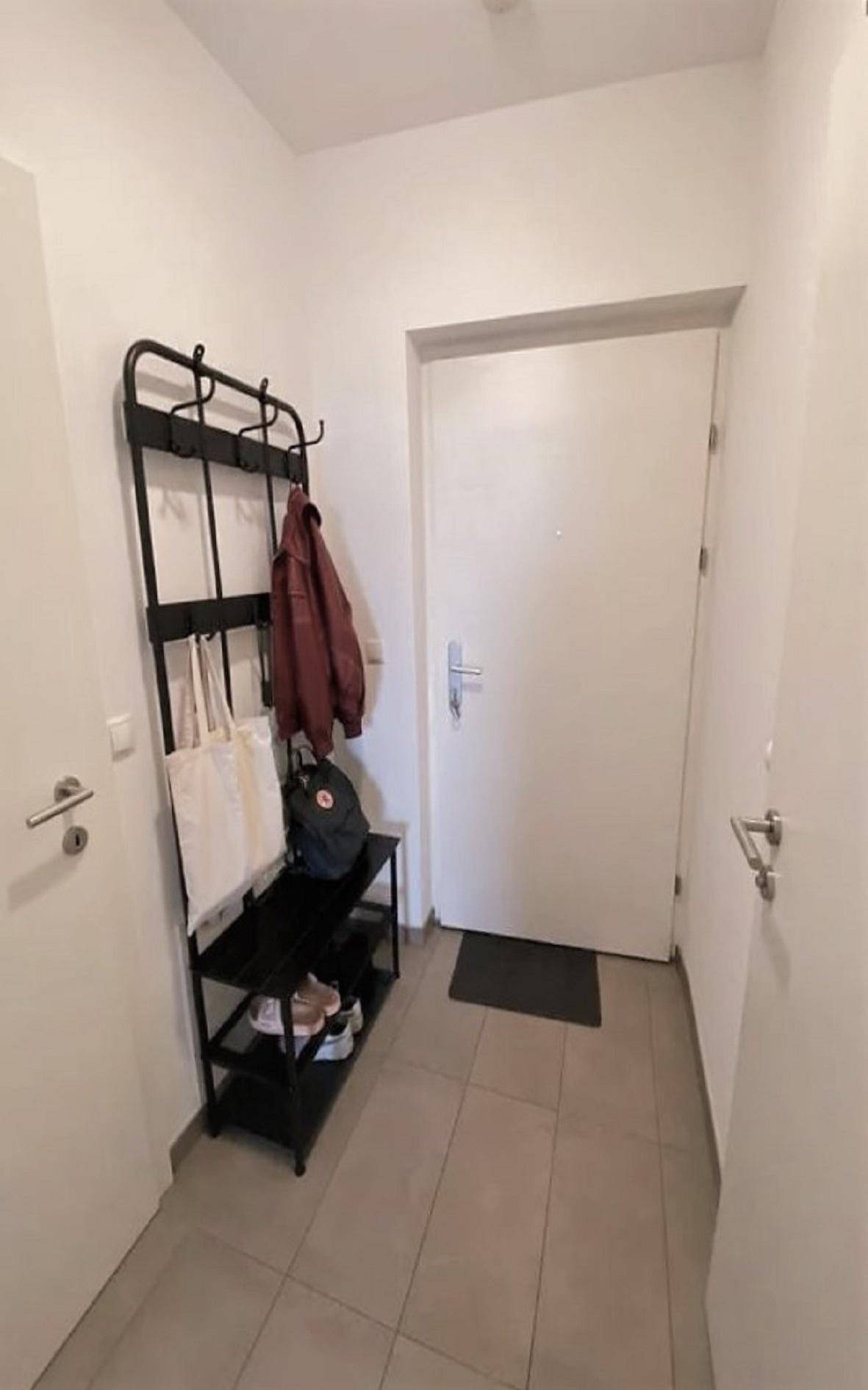 Heller Eingangsbereich mit praktischer Garderobe und Schuhregal, ideal für den Empfang von Gästen.