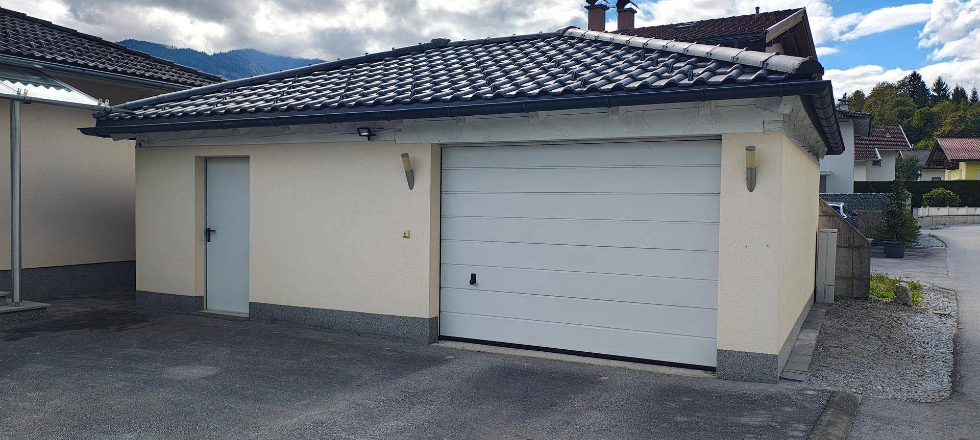 Separate Garage mit weißem Rolltor und zusätzlichem Seiteneingang.