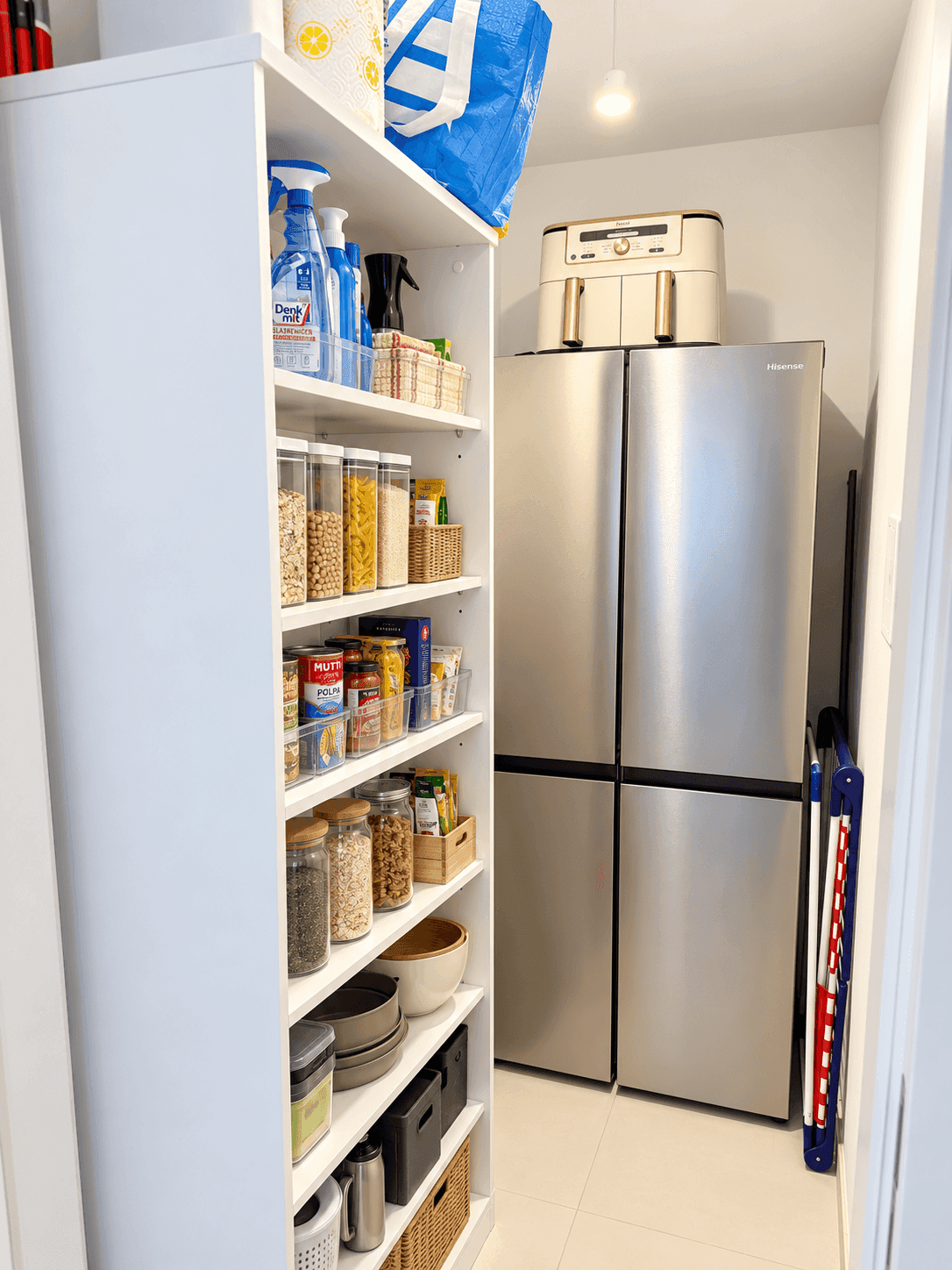 Praktischer Abstellraum mit Regalen für Vorräte und einem großen Kühlschrank.