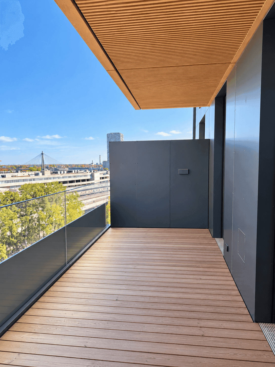 Geräumiger Balkon mit Holzboden und Glasgeländer bietet einen weiten Blick über die Stadt.