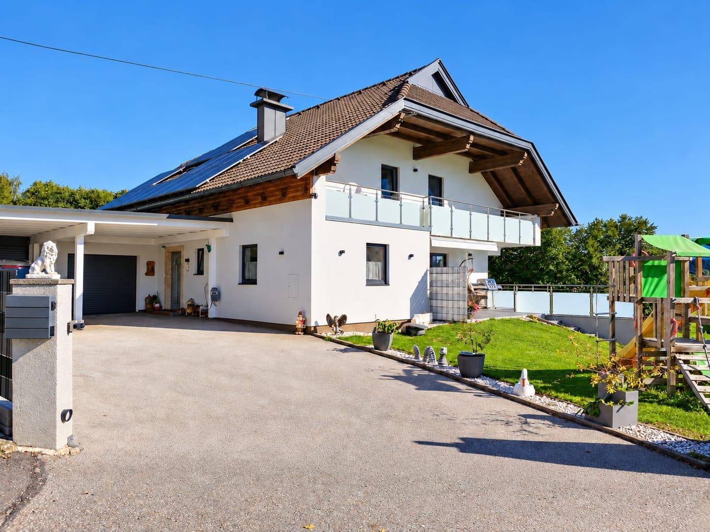 Modernes Einfamilienhaus mit Carport, Photovoltaikanlage auf dem Dach und gepflegtem Vorgarten.