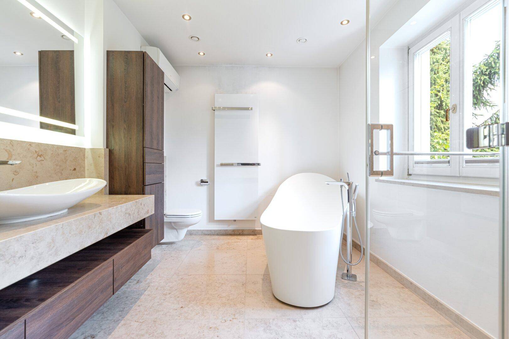 Modernes Badezimmer mit freistehender Badewanne, begehbarer Dusche und Doppelwaschbecken auf Marmorplatte.