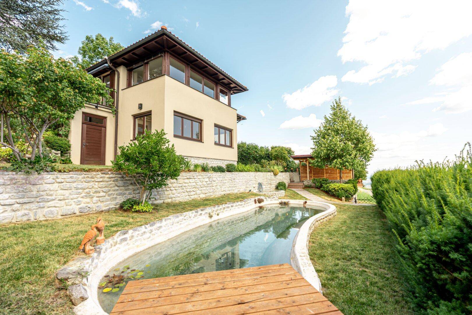 Haus mit Außenpool und gepflegtem Gartenbereich, umgeben von Natur und mit weitem Blick.